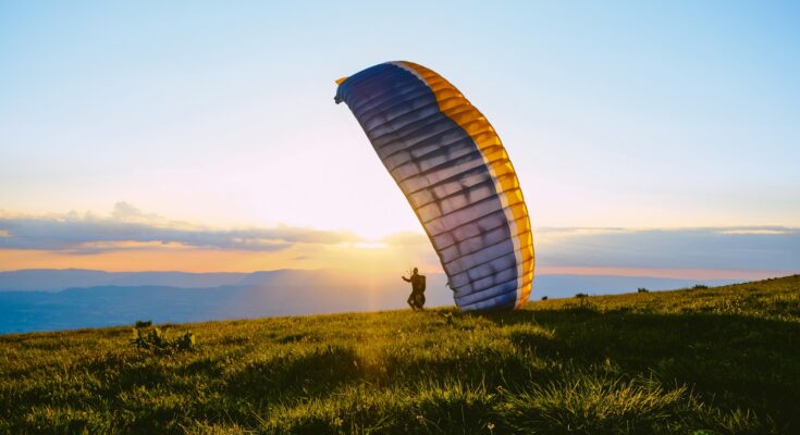 silhouette of person riding parachute during sunset