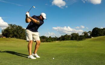 man in black shirt and white shorts playing golf during daytime
